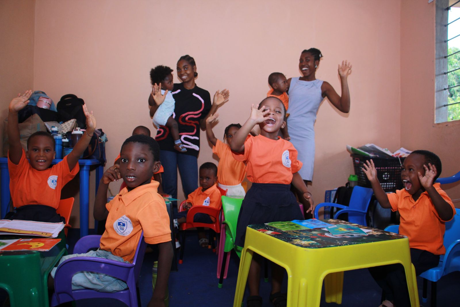Children and teachers waving happily in the classroom